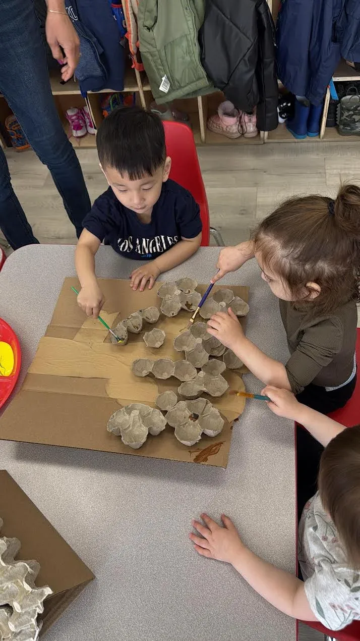 Children painting a group project made from cardboard and egg cartons