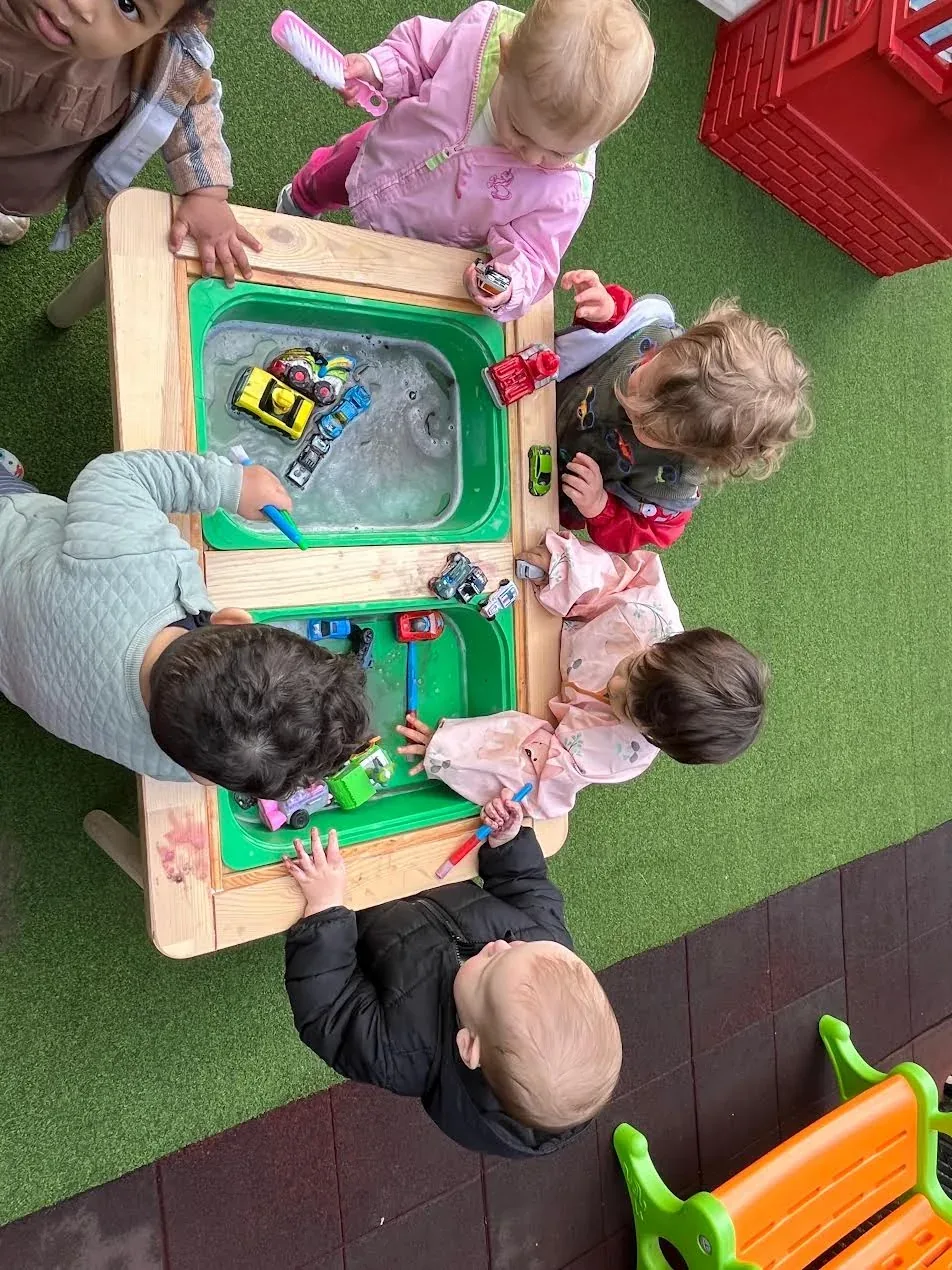 Children washing toy cars together at an outdoor water table
