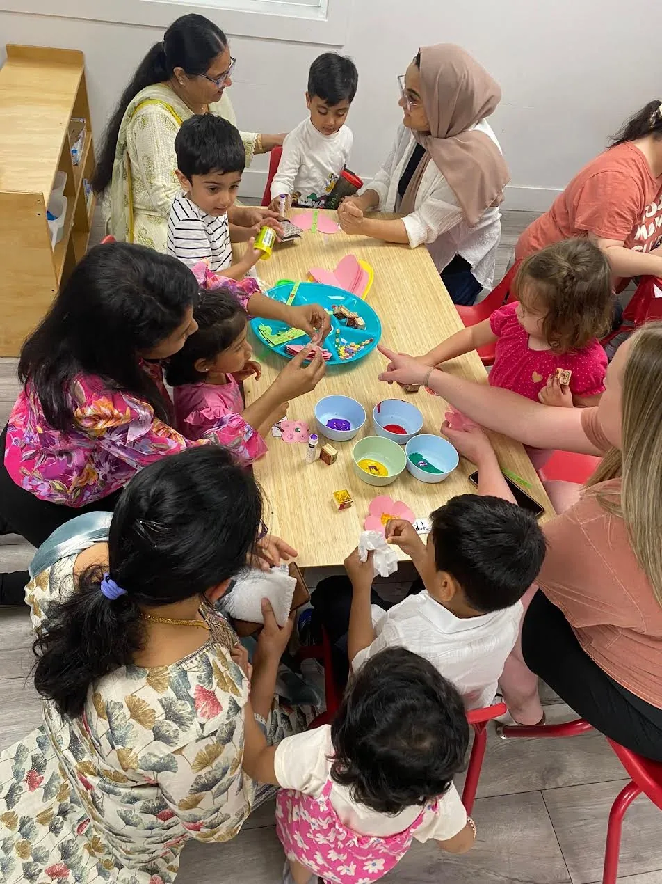 Children and educators gathered around a table for a group craft activity